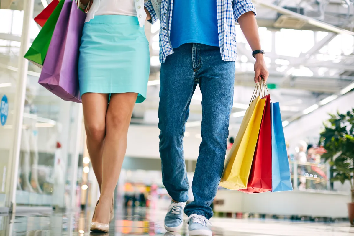 Casal caminhando com sacolas de compras em corredor de shopping moderno em Santiago do Chile.