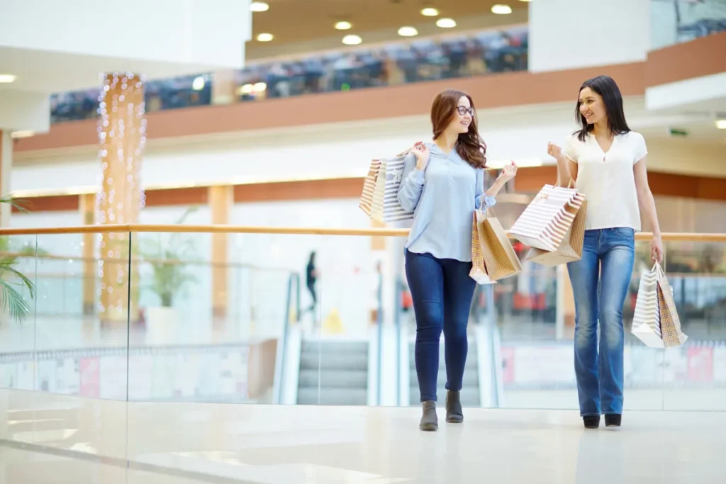 Duas mulheres caminhando com sacolas em shopping center durante passeio de compras em Santiago.