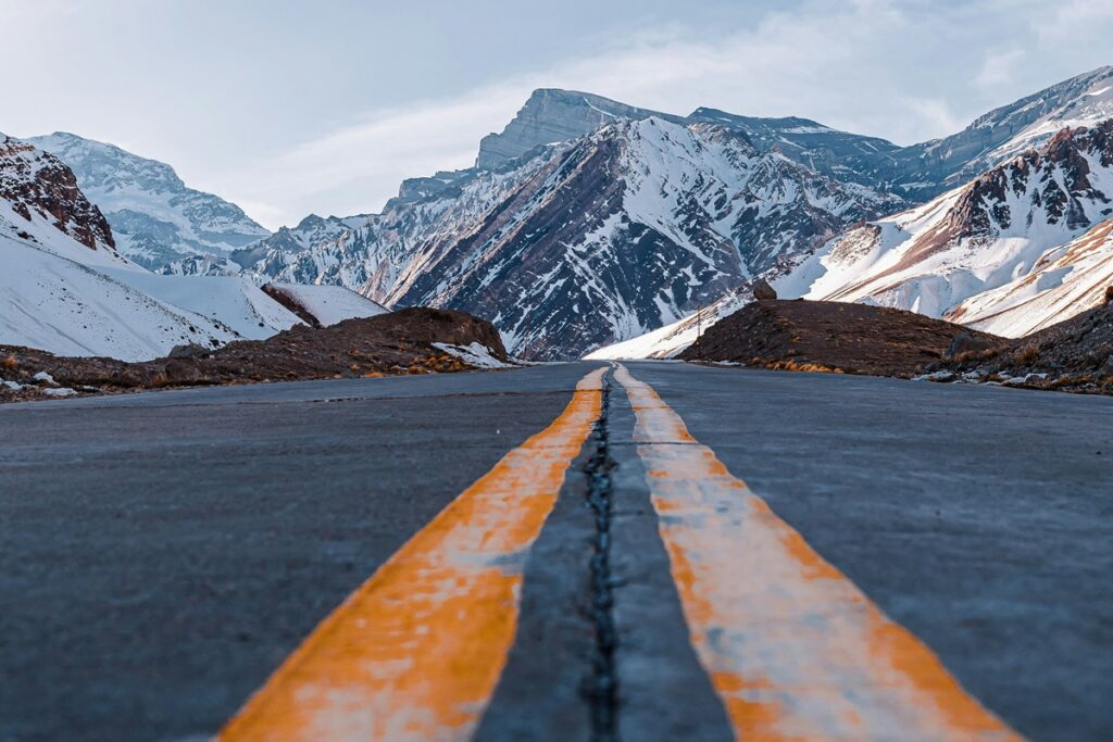 Estrada asfaltada atravessando montanhas nevadas da Cordilheira dos Andes.
