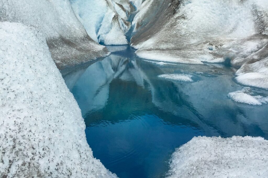 Pequeno lago azul cercado por formações de gelo em uma geleira da América do Sul.