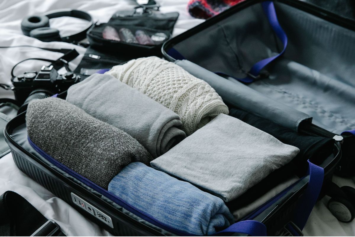 Mala aberta com roupas e acessórios sendo organizados para uma viagem