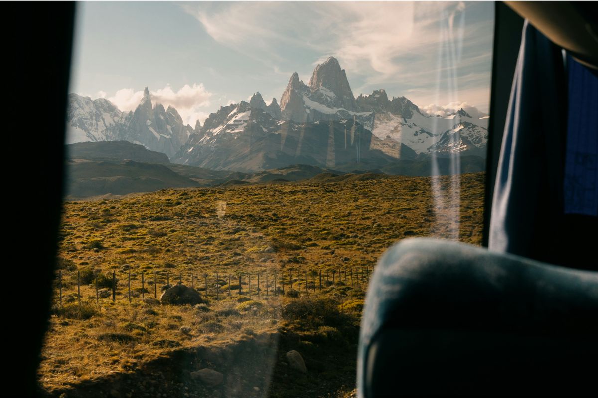 Excursão: o que é, como funciona e o que avaliar antes de contratar Montanhas da Patagônia vistas pela janela de um ônibus próximo a El Chaltén