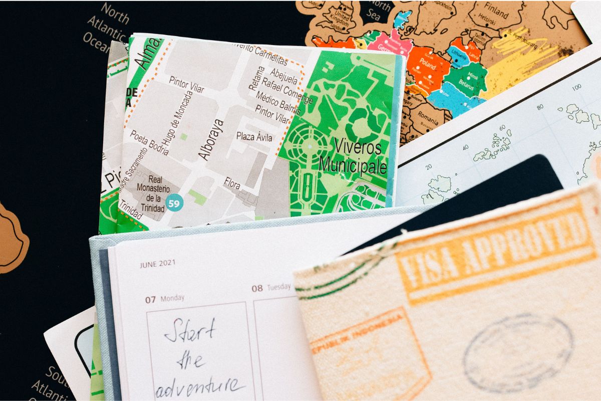 Excursão: o que é, como funciona e o que avaliar antes de contratar Planner aberto sobre mapas com bússola e documentos ilustrativos de viagem