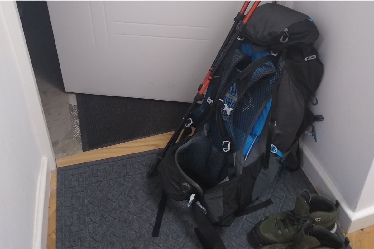 Mochila de trekking acompanhada de bastões de caminhada e calçados