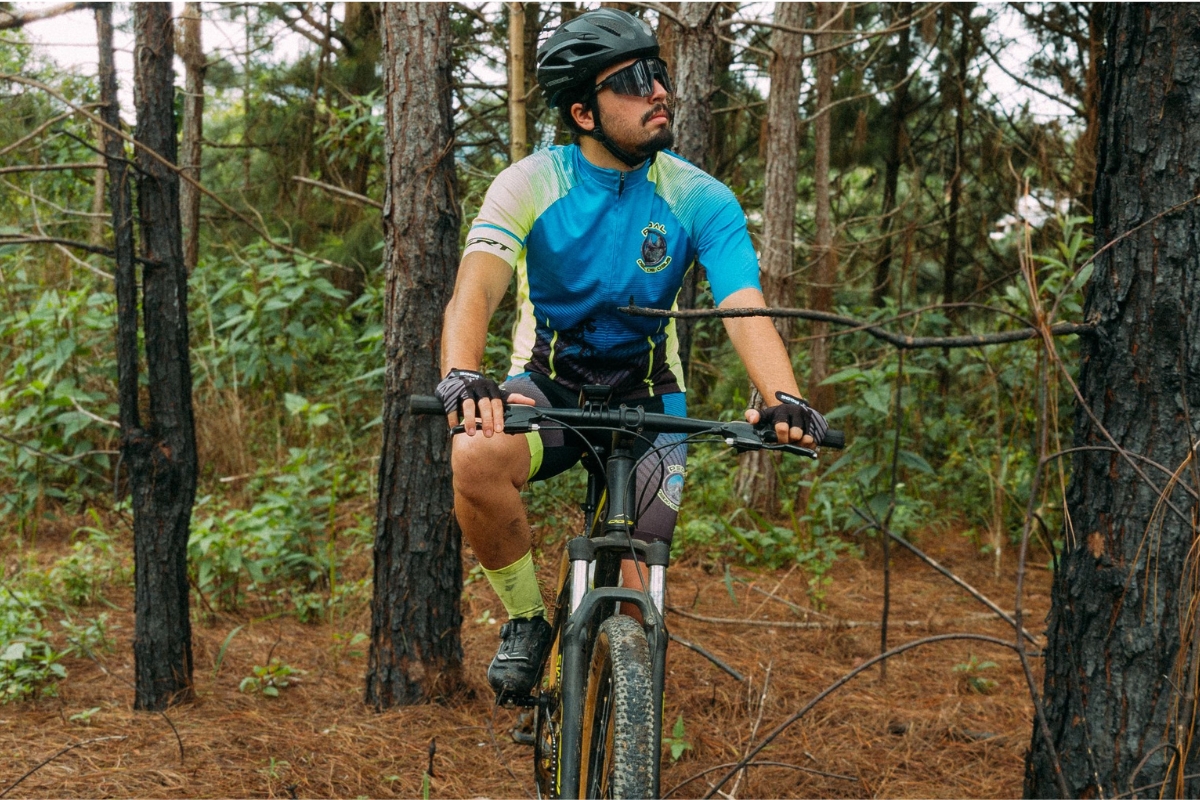 Ciclista conduz mountain bike por uma trilha em área de floresta