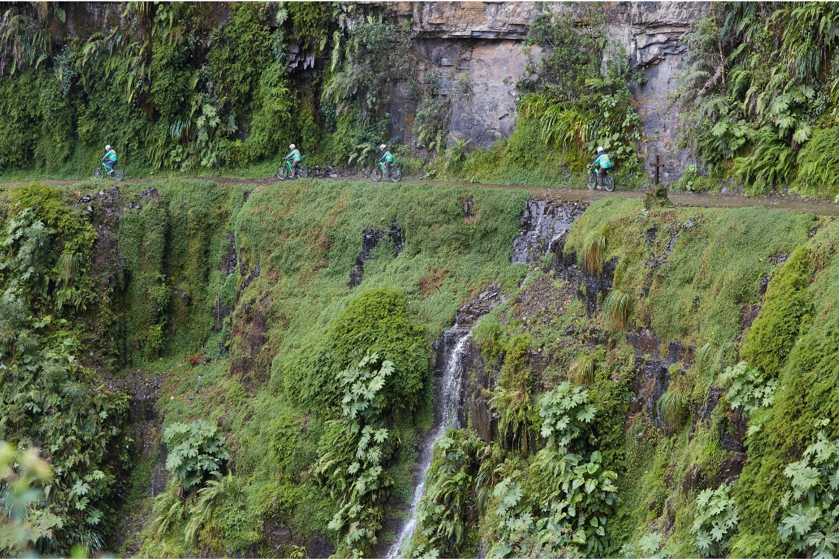 Ciclistas percorrem a estrada dos Yungas em encosta montanhosa na Bolívia