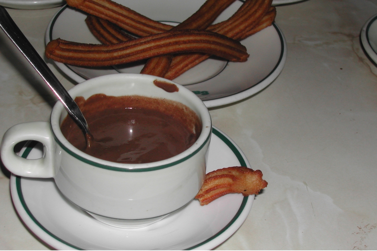 Chocolate quente servido com churros em uma mesa