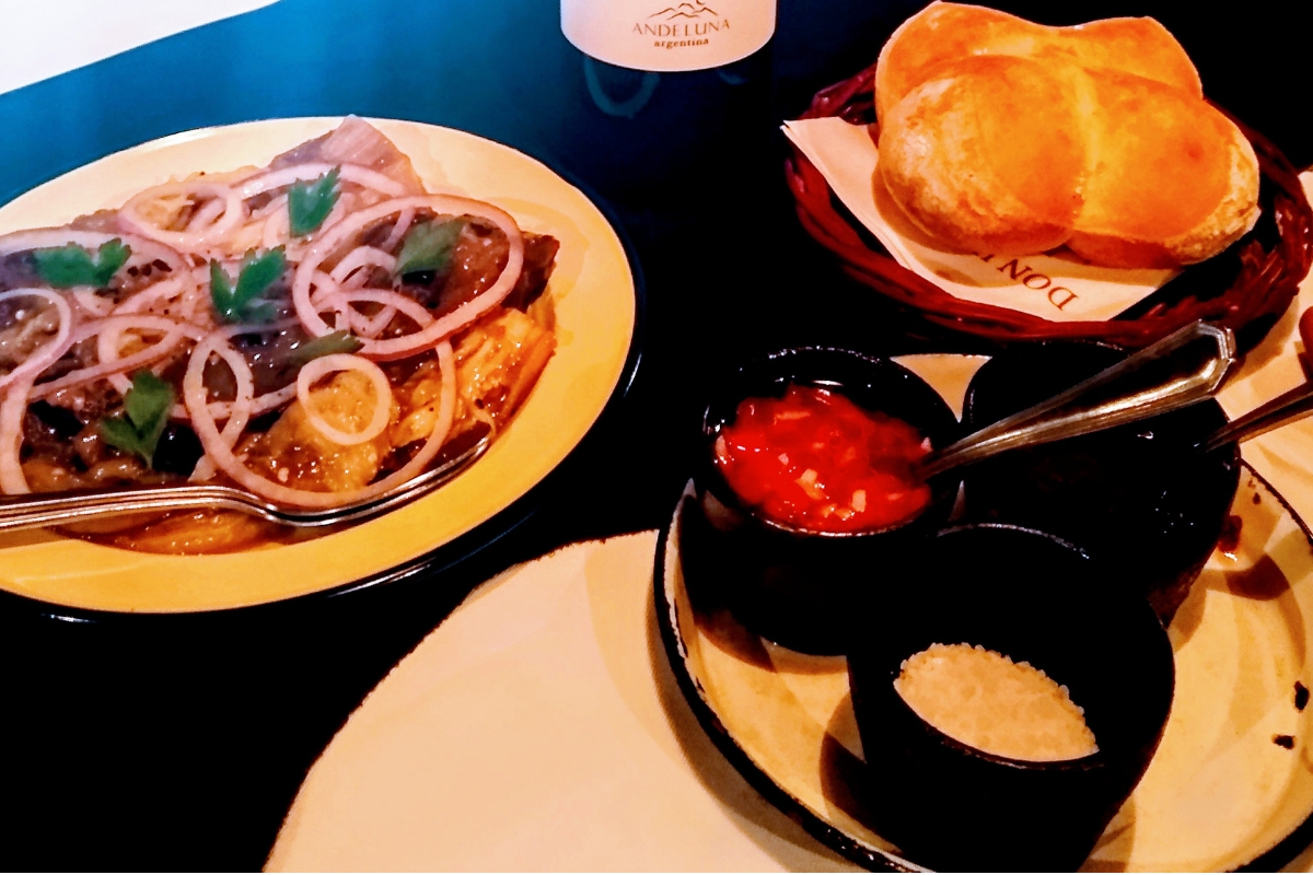 Mesa no Don Julio com entrada de vegetais, pão e vinho argentino