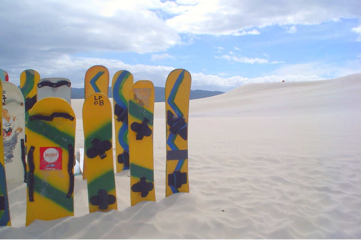Pranchas de sandboard apoiadas na areia, com formatos diferentes.