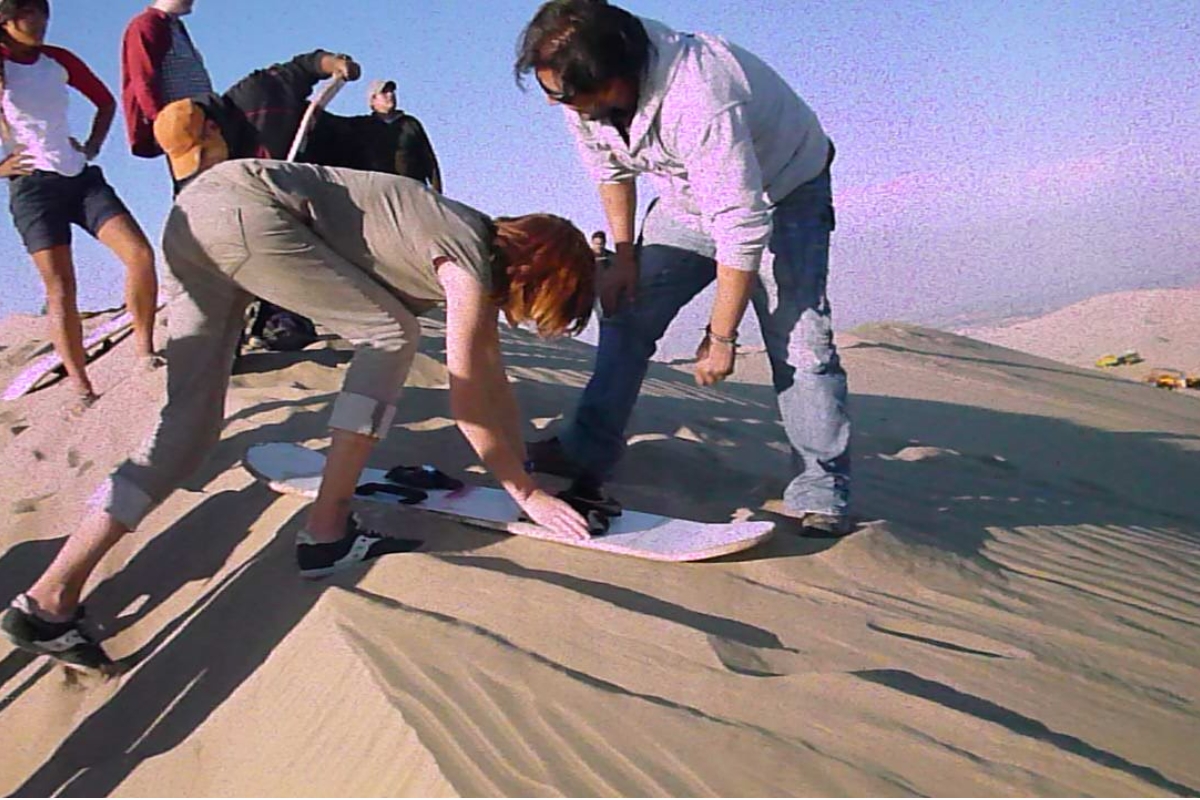 Turistas praticando sandboard em uma duna de Huacachina, no Peru.