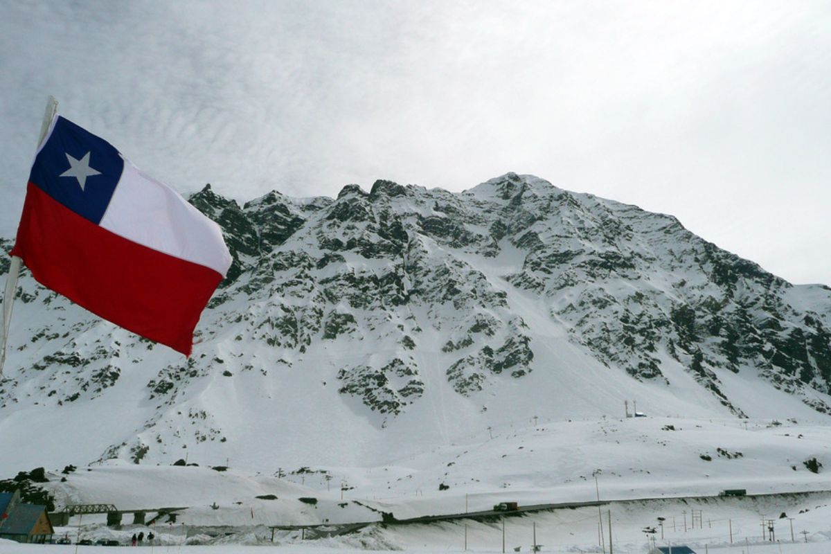 Montanha coberta de neve e bandeira chilena na região de Portillo