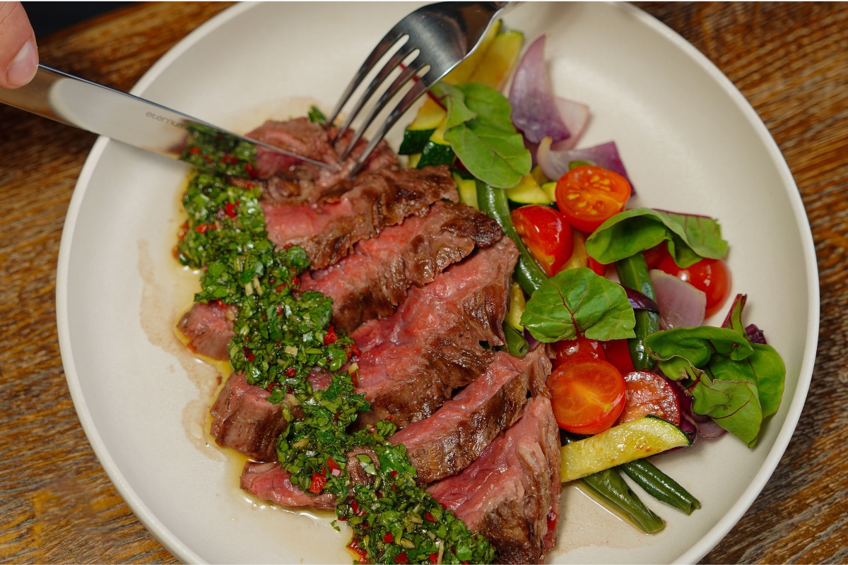 Steak fatiado servido com chimichurri e vegetais
