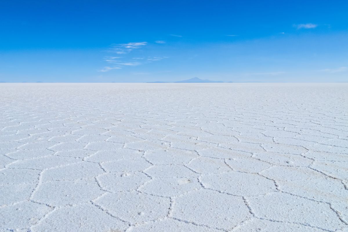 Padrões hexagonais de sal no Salar de Uyuni com o vulcão Tunupa ao fundo