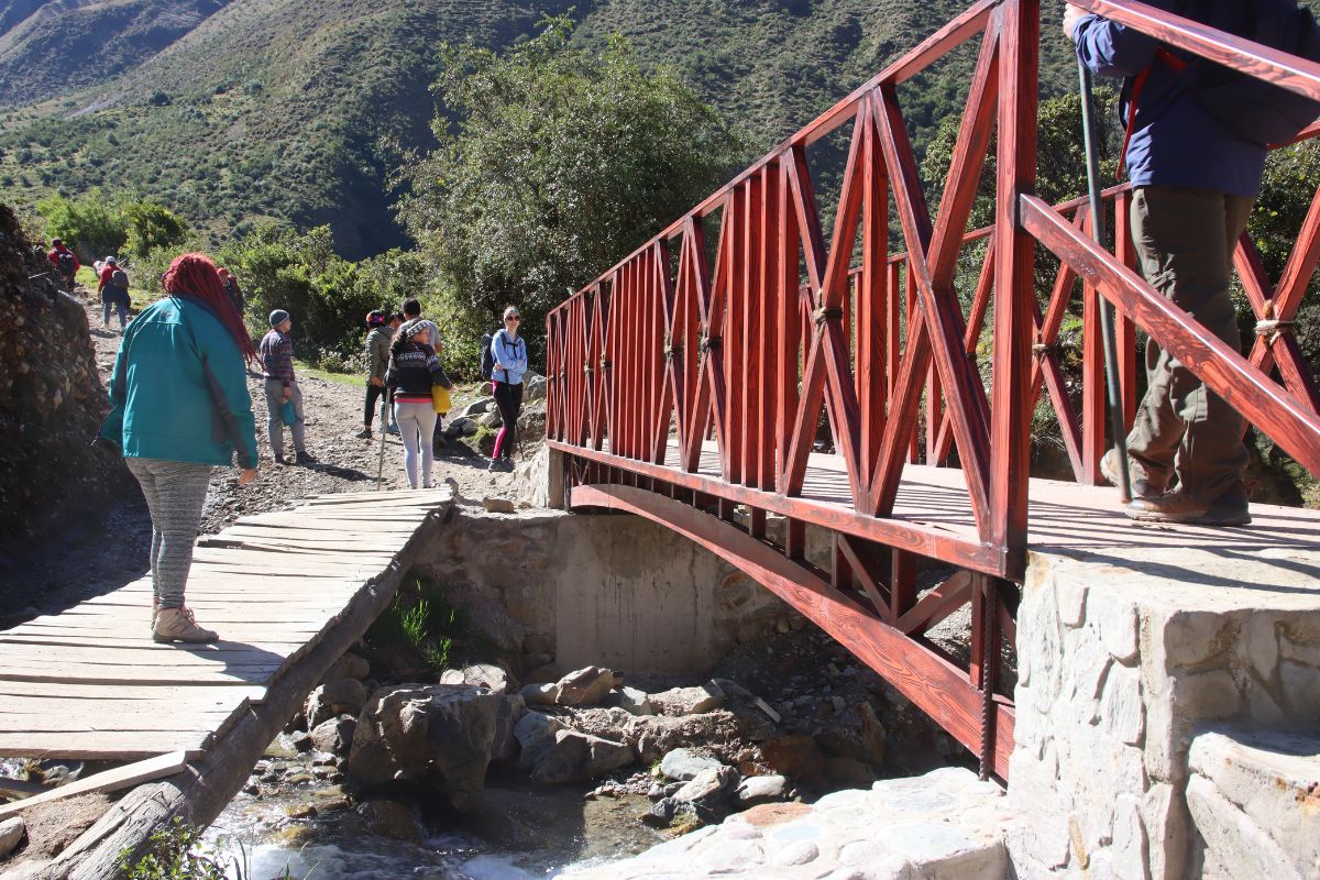 Caminhantes atravessando uma ponte de acesso na área de Soraypampa