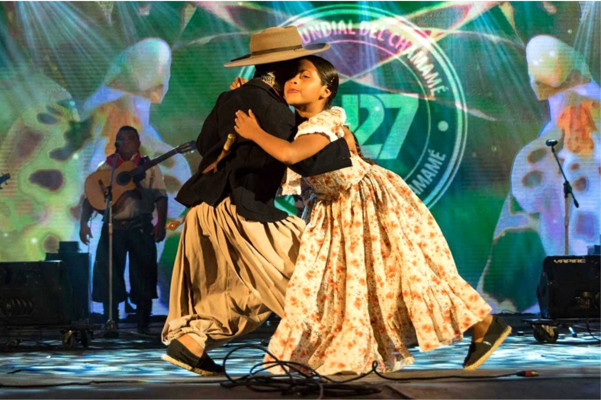 Casal dançando chamamé em abraço fechado durante apresentação cultural