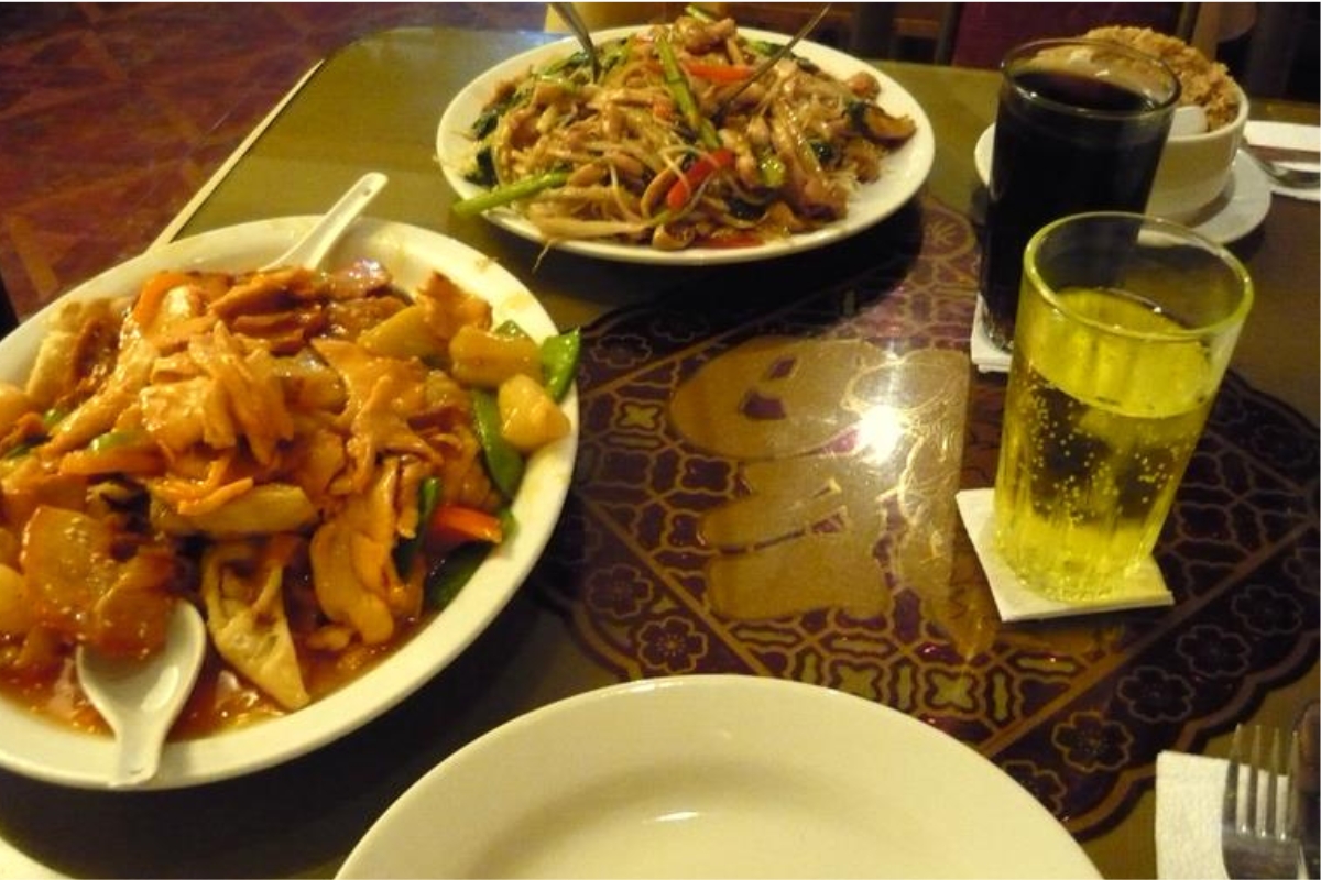 Mesa de chifa com pratos da culinária sino-peruana e copo com bebida amarela