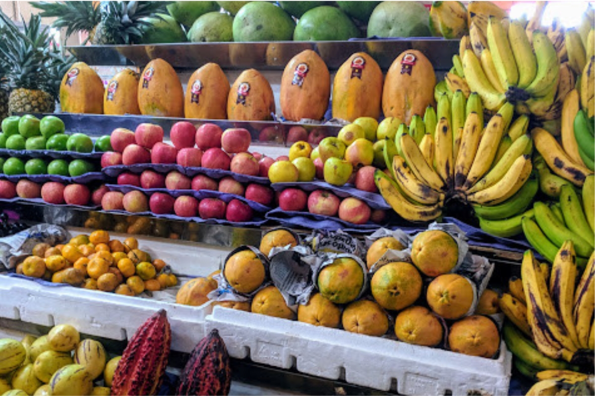 Banca de frutas no Mercado Central de Quito com bananas, mamões, cítricos e outras frutas em exposição.