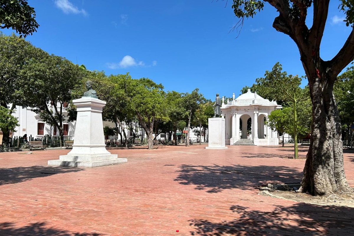 Parque de los Novios no Centro Histórico de Santa Marta, com praça arborizada, monumentos e coreto branco.