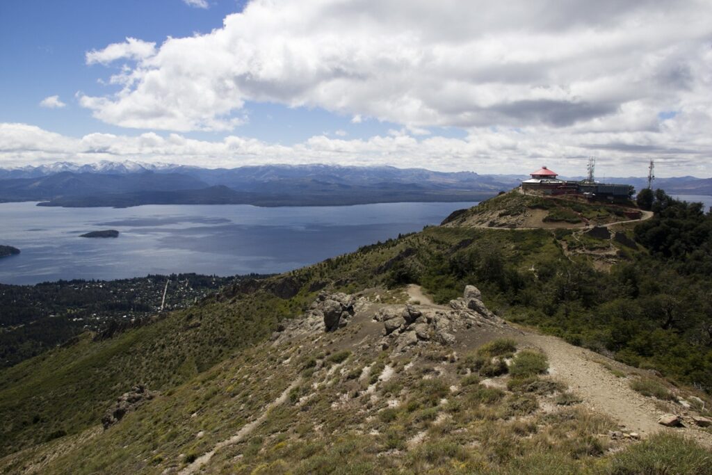 Vista do Cerro Otto com o lago Nahuel Huapi, montanhas ao fundo e estrutura turística no alto do morro.