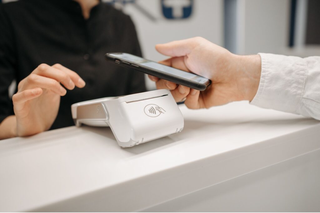 Pix no exterior: como funciona, taxas, limites e cuidados Pessoa aproxima um smartphone de uma máquina de pagamento por aproximação em um estabelecimento comercial.
