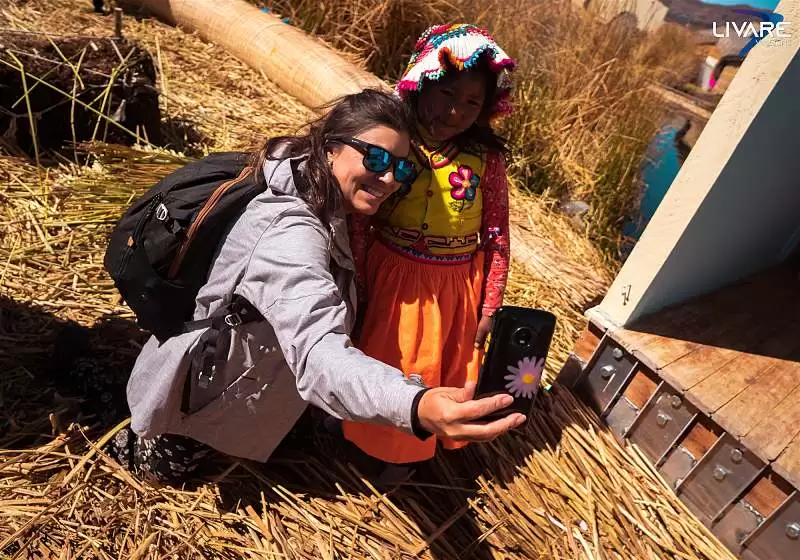 mulher sorrindo tirando selfie com menina indígena